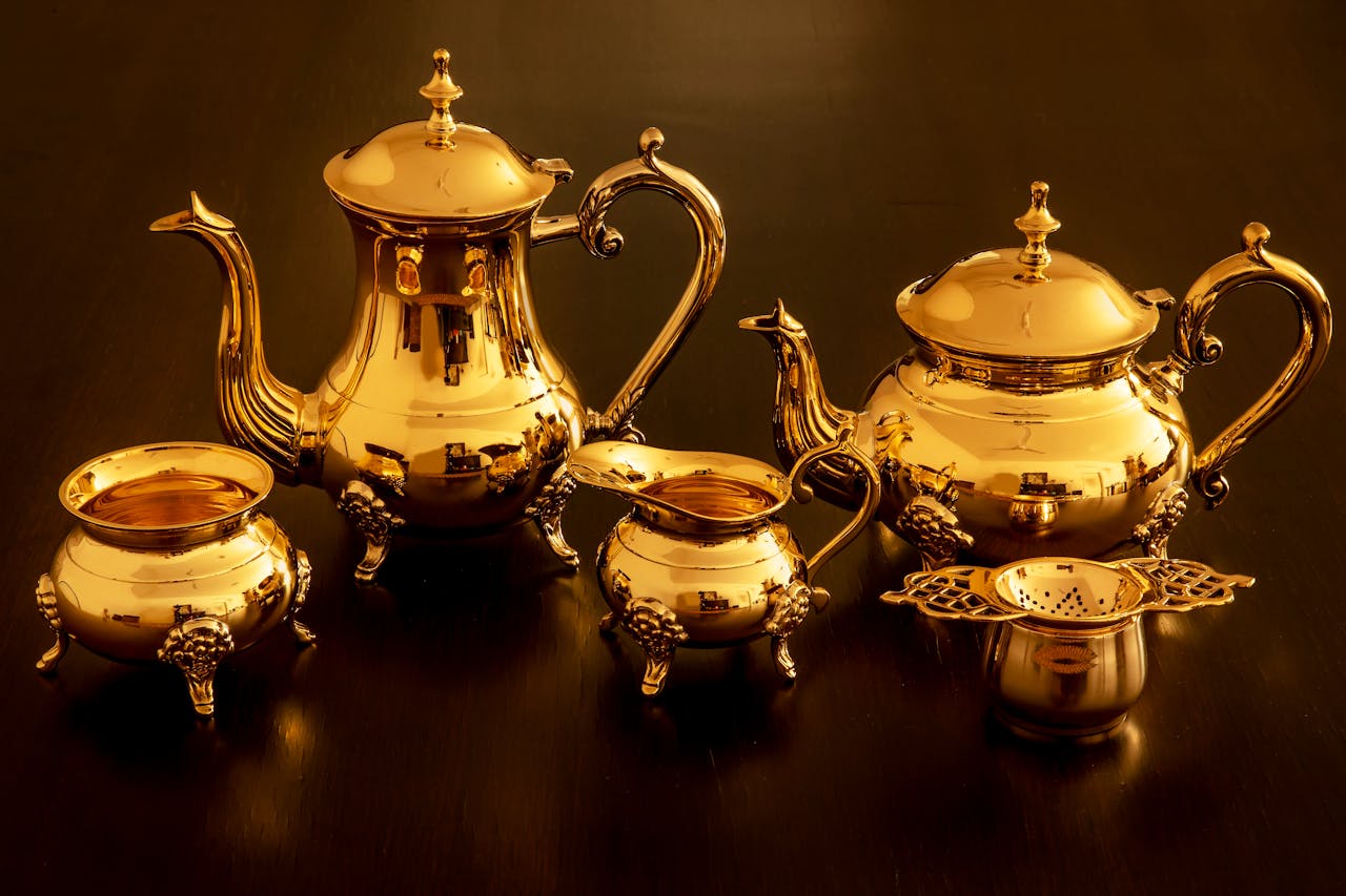 home-img A luxurious golden teapot set with intricate designs beautifully arranged on a dark surface.